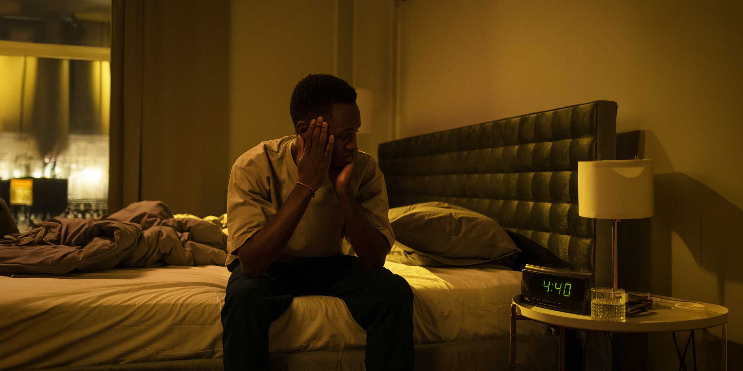 Man awake in his bedroom at 4:40 am looking frustrated