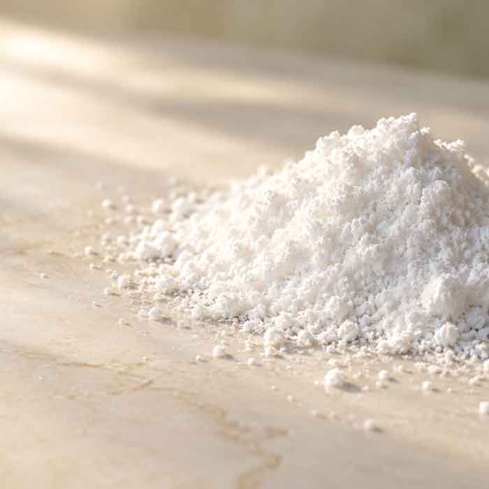 A pile of fine white beta-sitosterol powder on a pale stone surface