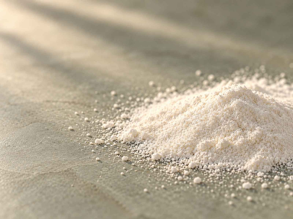 A mound of fine off-white vitamin B6 powder on a warm grey stone surface