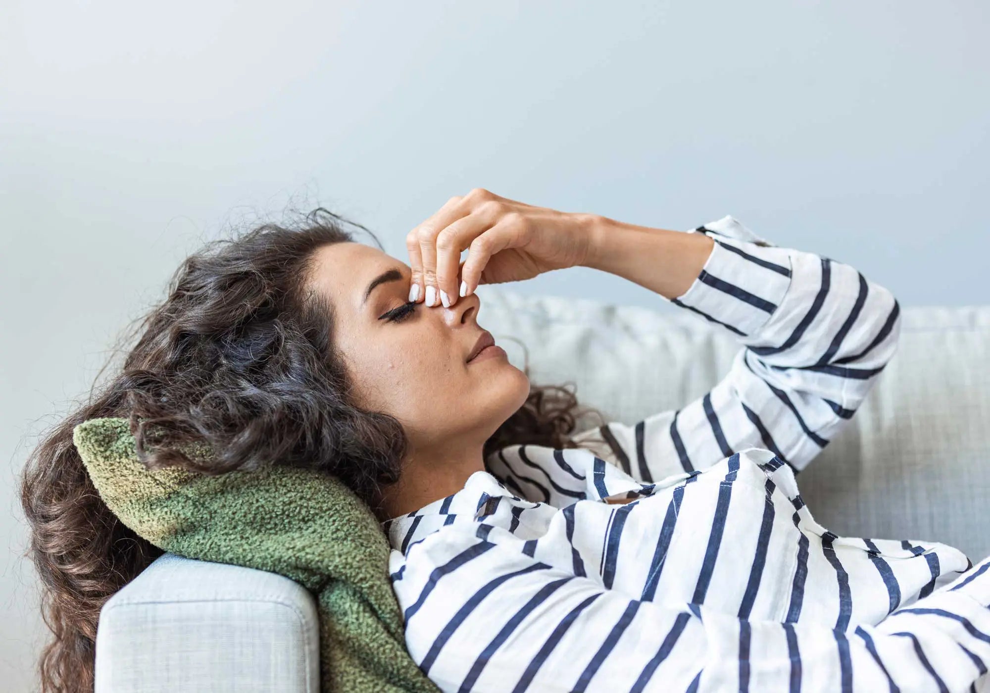 A woman resting on a sofa with her hand to her head