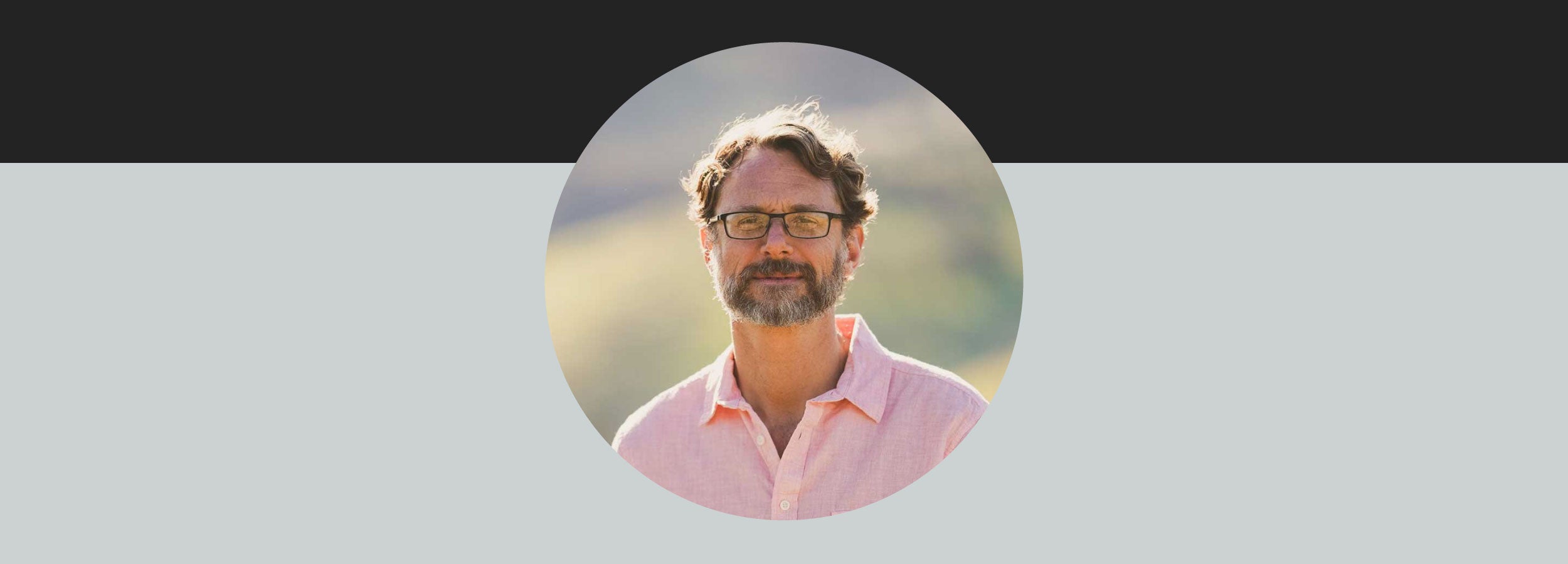 Circular profile picture of a man with glasses and a beard on a light gray background