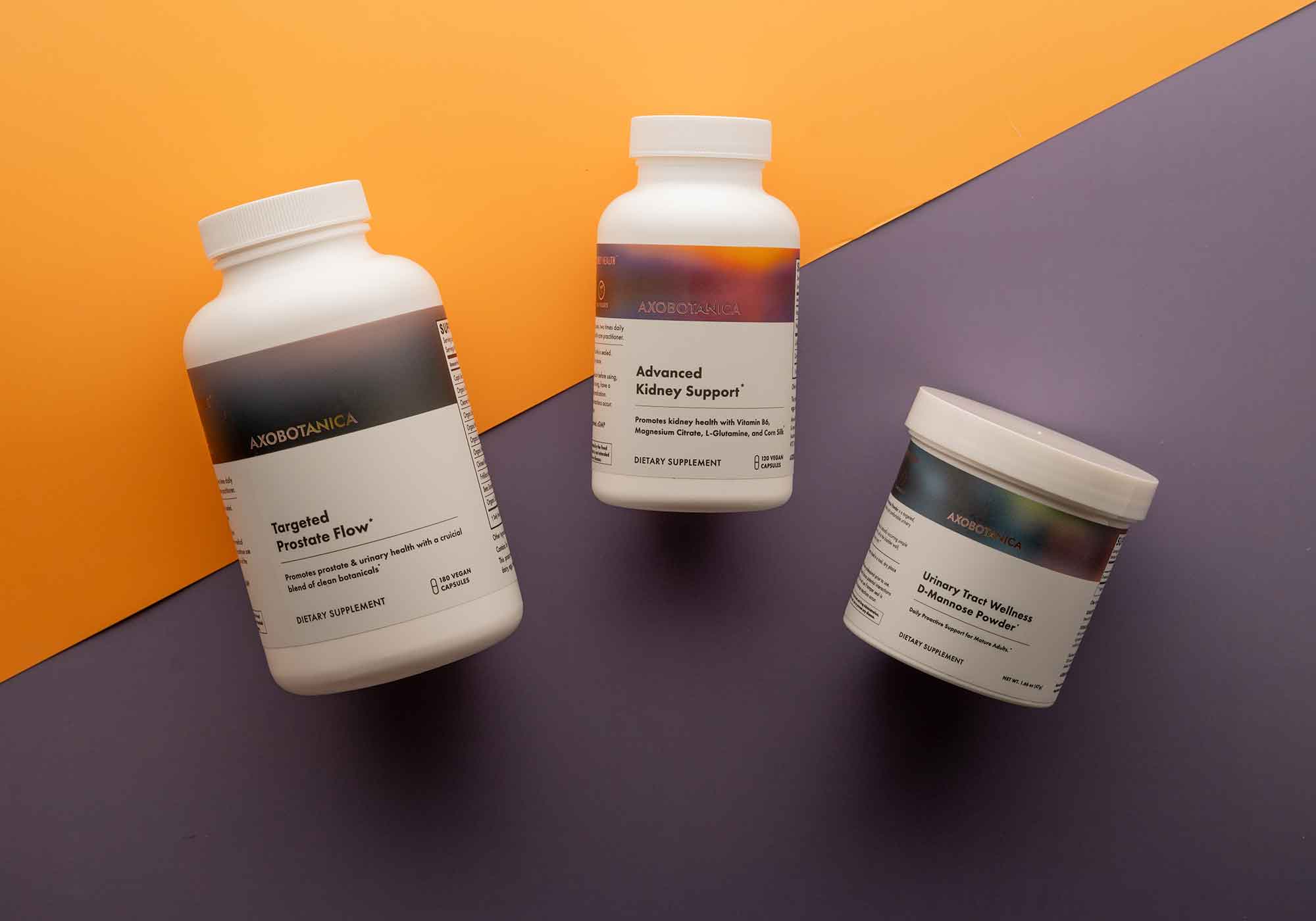 Three supplement bottles on a two-tone orange and purple background