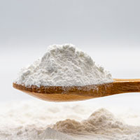 Wooden spoon filled with white powder against a light gray background