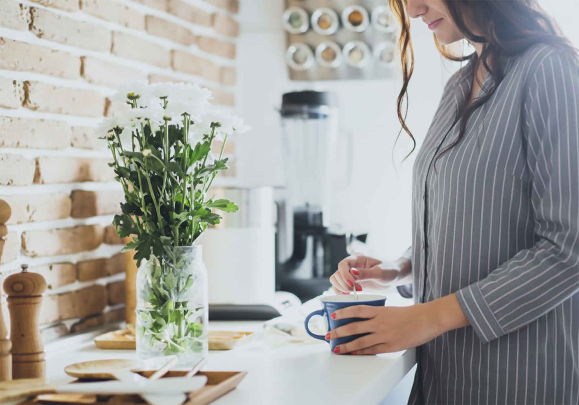 Woman standing in kitchen making coffee